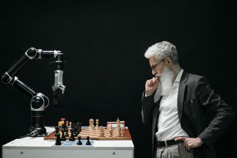 Man playing chess against a robot. 